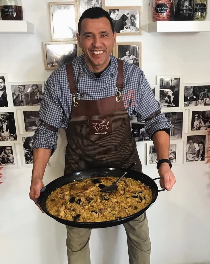 Chaouki, cocinero y dueño del restaurante, sosteniendo una paella recién hecha