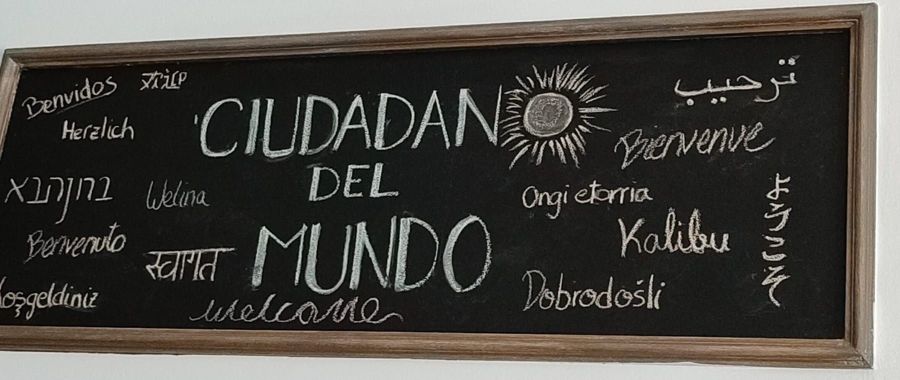 Pizarra de madera con la palabra "bienvenido" escrita con tiza en veinte idiomas