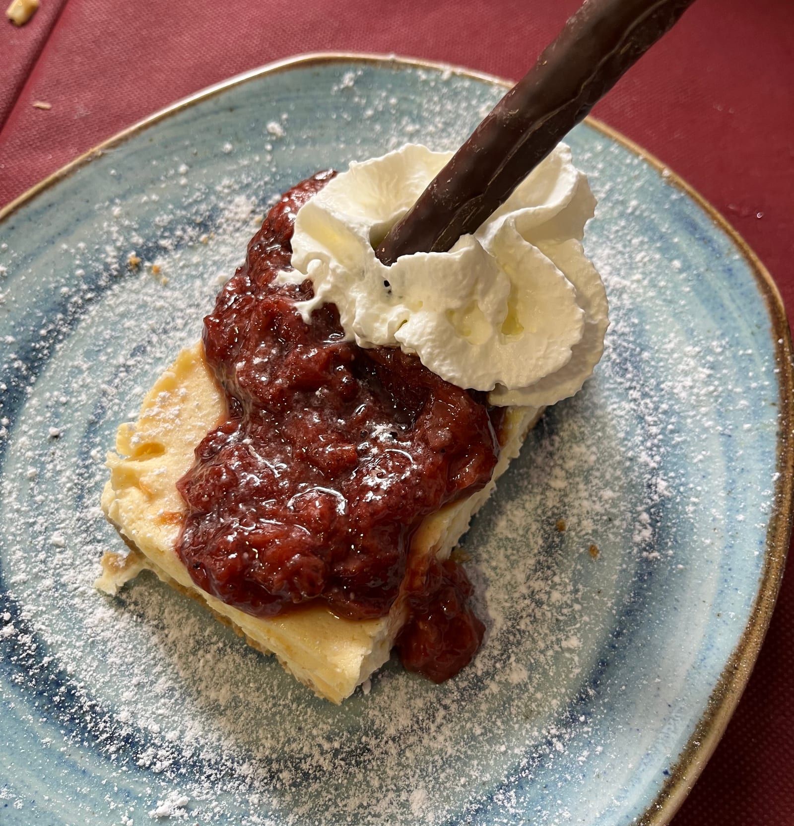 Tarta de queso con mermelada de frutos rojos y nata, espolvoreada con azúcar