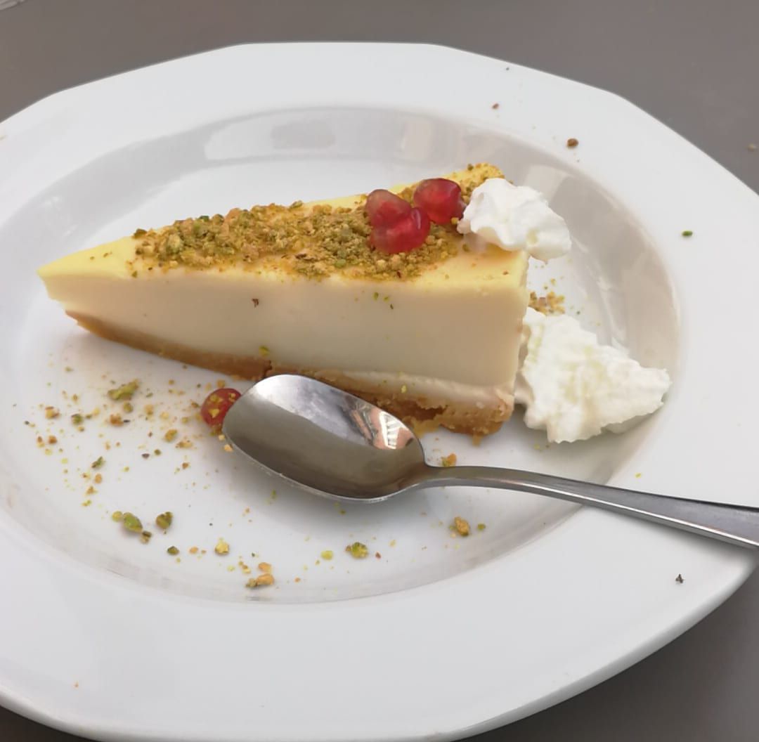 Porción de tarta de queso con pistacho picado y granos de granada